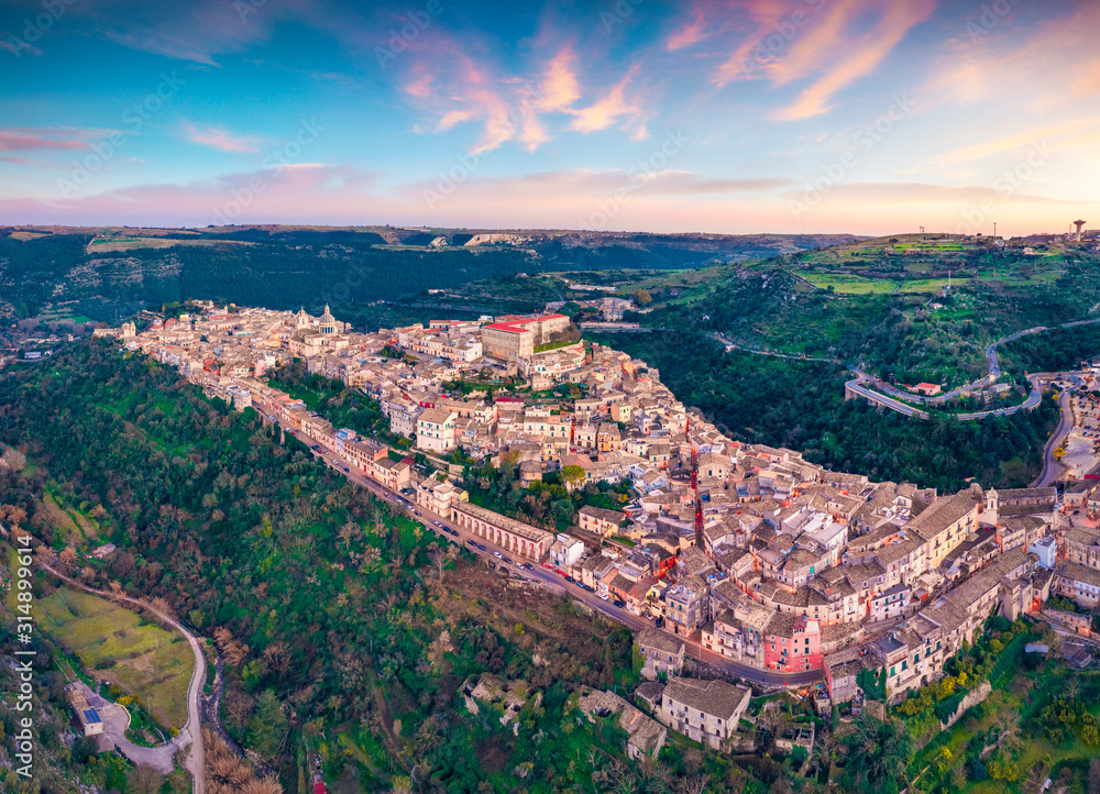 View from flying drone. Magnificent spring sunset in Ragusa town with Duomo San Giorgio - baroque Catholic church on background. Gorgeous evening scene of Sicily, Italy, Europe.