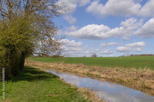 Landscape with a footpath alonside a stream looking over farmland in england.