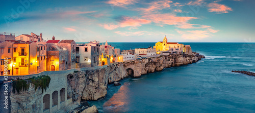 Exotic evening cityscape of Vieste - coastal town in Gargano National Park, Italy, Europe. Coloful spring sunset on Adriatic sea. Traveling concept background.