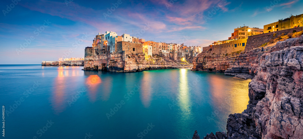 Panoramic evening cityscape of Polignano a Mare town, Puglia region, Italy, Europe. Amazing  spring sunrise view of Adriatic sea. Traveling concept background.