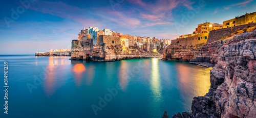 Panoramic evening cityscape of Polignano a Mare town, Puglia region, Italy, Europe. Amazing spring sunrise view of Adriatic sea. Traveling concept background.