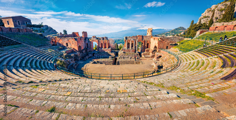 Naklejka premium Panoramic morning view of Taormina town and Etna volcano on background. Picturesque spring view of ancient Greco-Roman theater, Sicily, Italy, Europe. Traveling concept background.