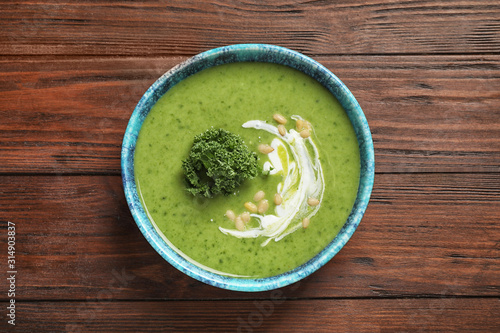 Tasty kale soup with pine nuts on wooden table, top view