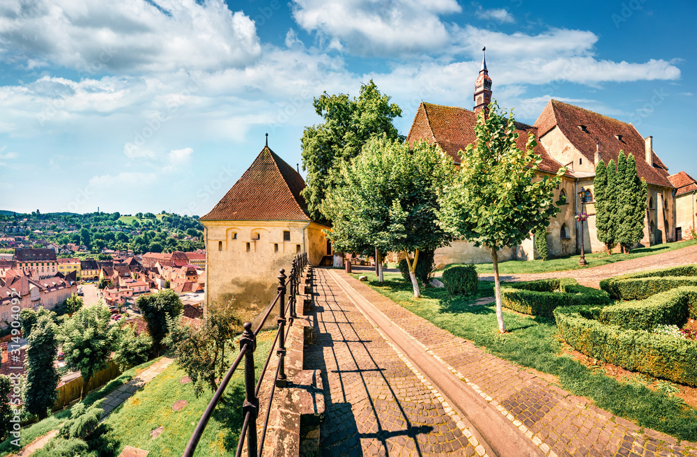 Amazing morning cityscape of Sighisoara with Evangelical Church on background. Sunny summer view of medieval town of Transylvania, Romania, Europe. Traveling concept background.