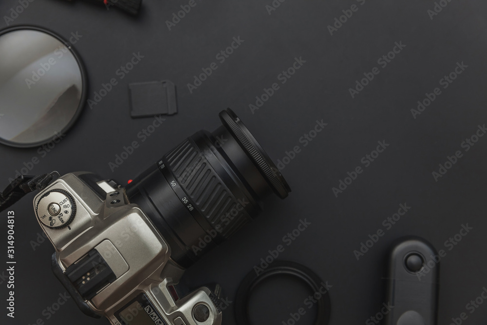 Fototapeta premium Photographer workplace with dslr camera system, camera cleaning kit, lens and camera accessory on dark black table background. Hobby travel photography concept. Flat lay top view copy space.