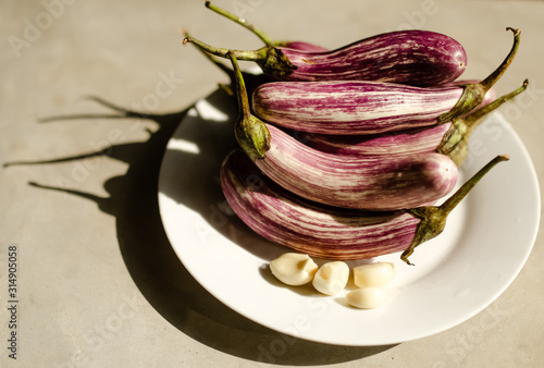 We prepare vegetables for the dish, young eggplant with garlic on a white plate