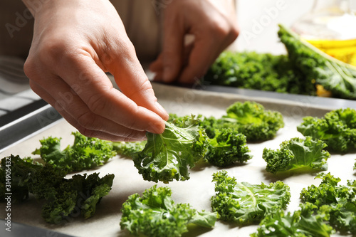 Woman preparing kale chips at table, closeup