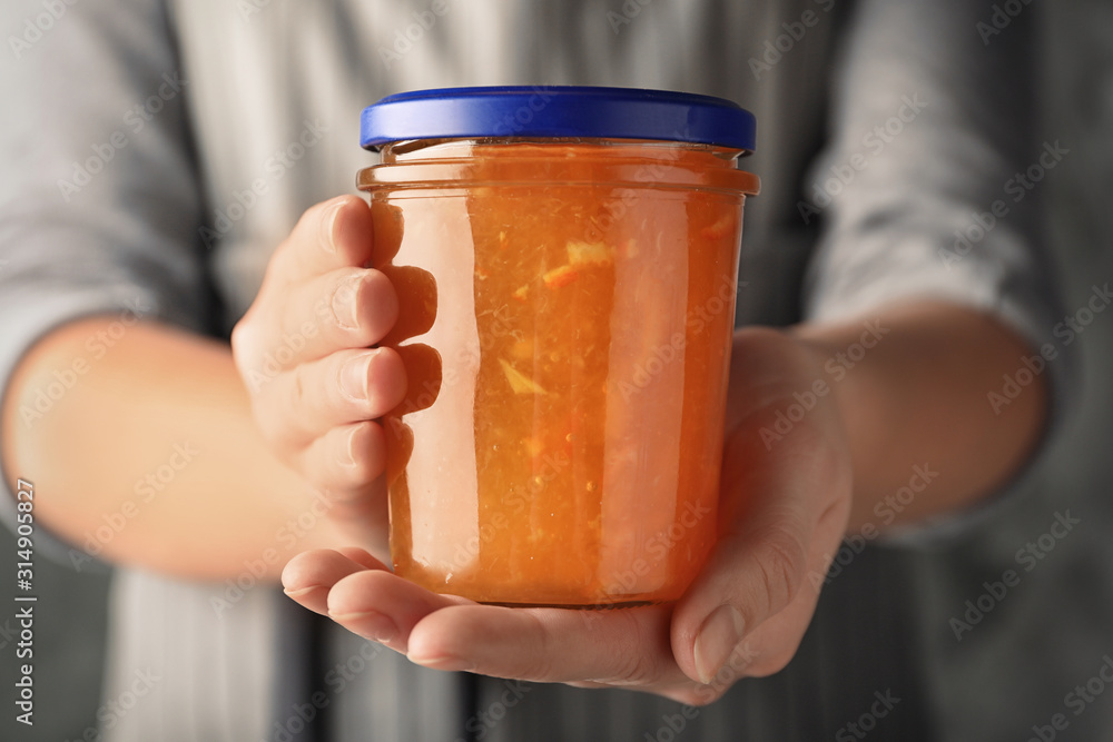 Woman with jar of orange jam, closeup Woman with jar of orange jam, closeup