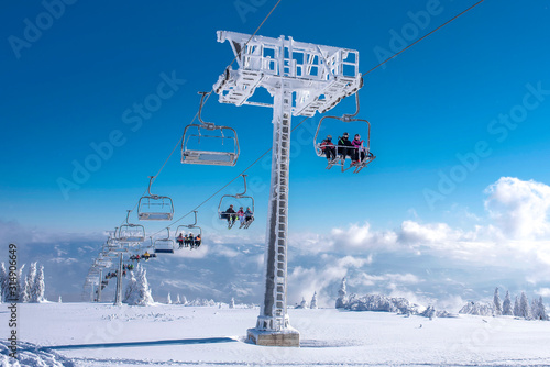 Skiers on chairlift at mountain ski resort with beautiful winter landscape in the background