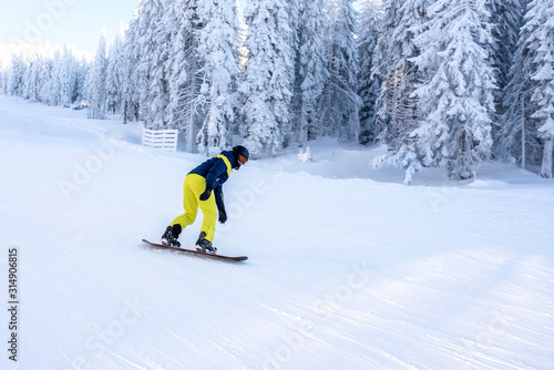 Snowboarder in motion, riding snowboard down the hill in mountain ski resort