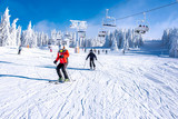 People enjoying skiing and snowboarding in mountain ski resort with beautiful winter landscape in the background