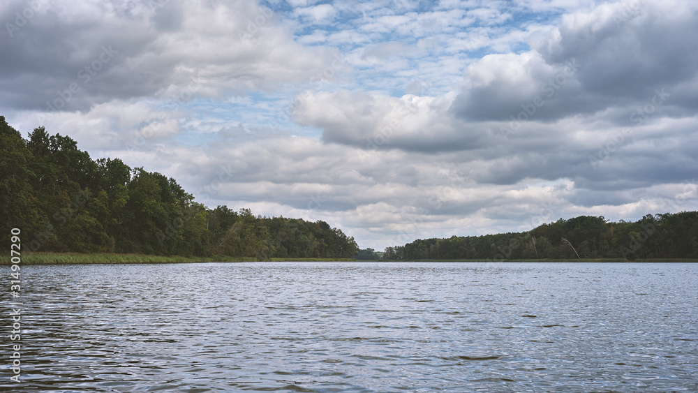 Cloudy summer weather at a lake in the middle of a dense forest.