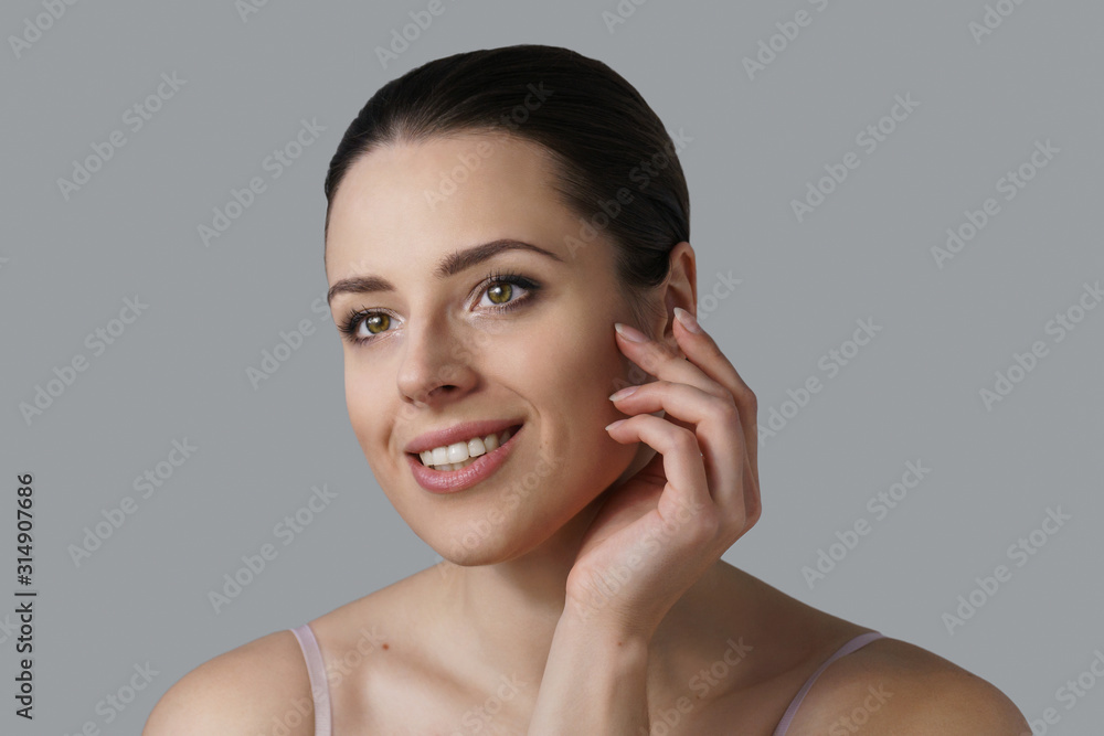 Portrait of young brunette smiling slightly touching her cheek Portrait of young brunette smiling slightly touching her cheek