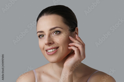 Portrait of young brunette smiling slightly touching her cheek