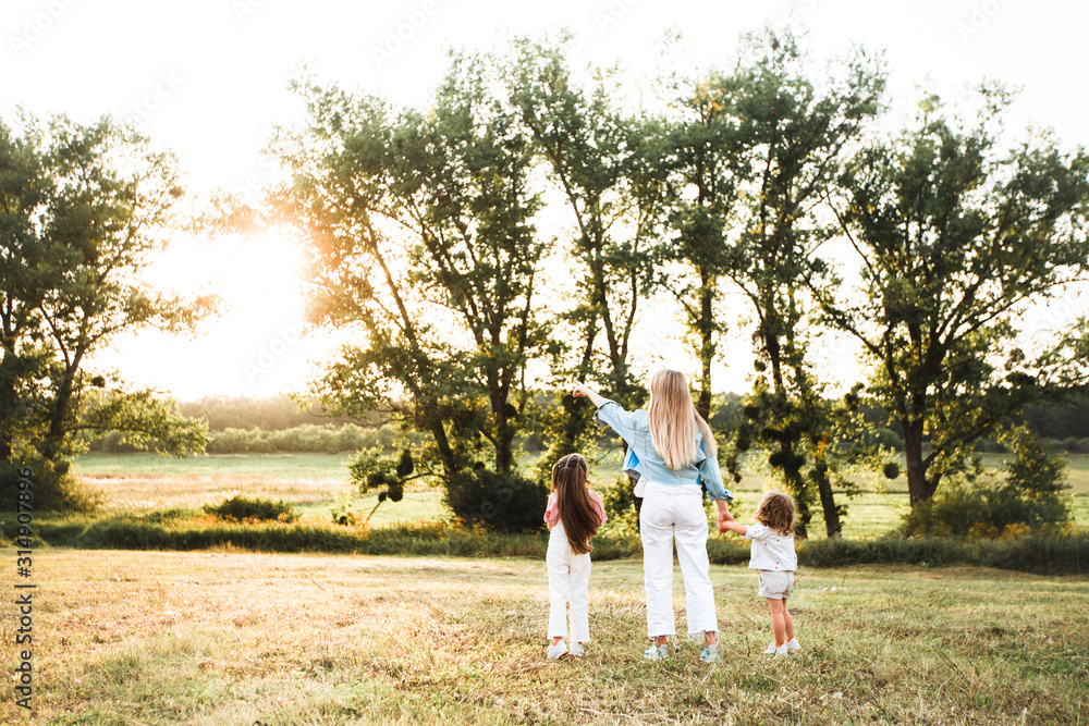 Blonde mother with two cute daughters are walking and having fun outdoors. Stylish, casual clothes. Blonde mother with two cute daughters are walking and having fun outdoors. Stylish, casual clothes.