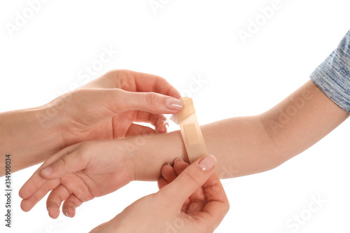 Mother putting sticking plaster onto son s arm on white background  closeup