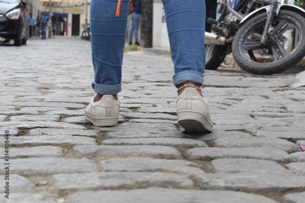 Mujer caminando con zapatillas sobre calle de piedras Stock Photo | Adobe  Stock