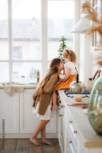 Two sisters play in a bright, stylish kitchen. Beautiful interior.