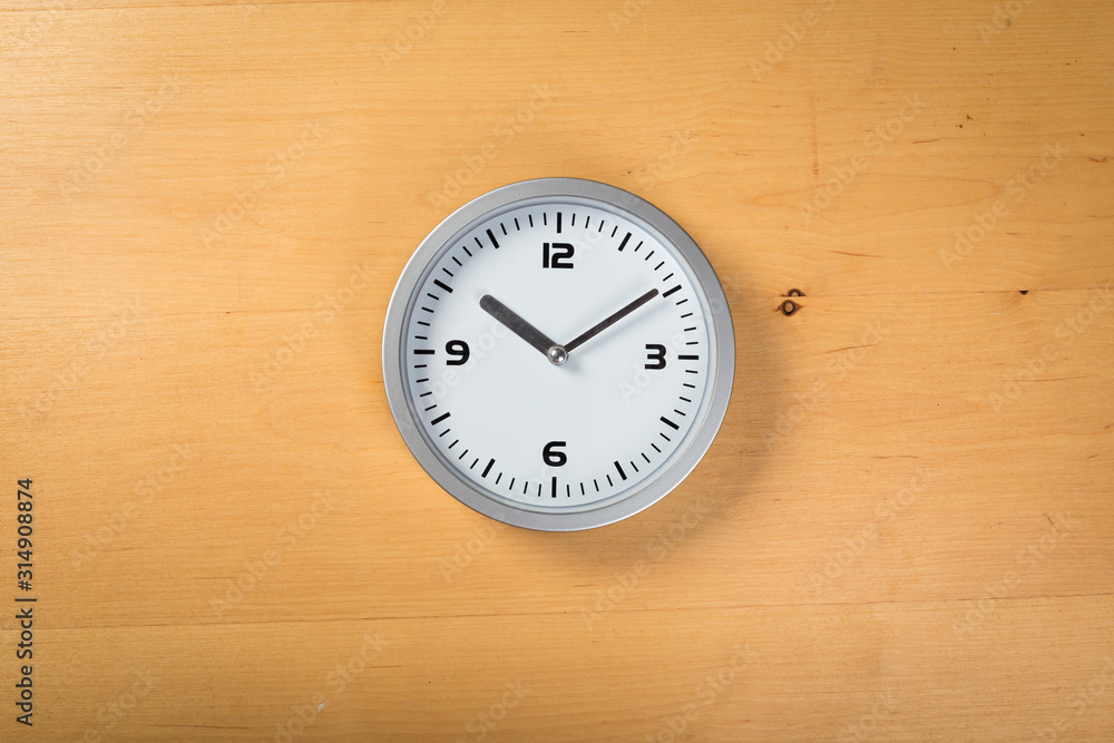 White wall clock with a yellow used hanging on the wall. Minimalist image of a wall clock on a wooden background with copy space White wall clock with a yellow used hanging on the wall. Minimalist image of a wall clock on a wooden background with copy space