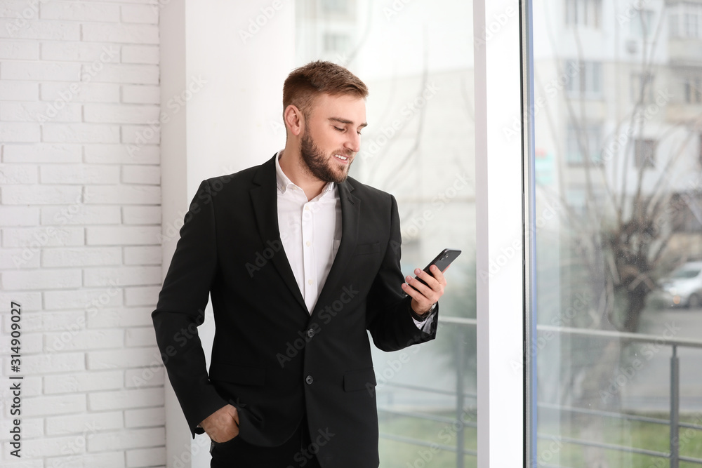 Young businessman using smartphone near window at home Young businessman using smartphone near window at home