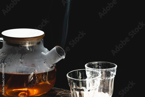 The steam from a cup or pot of coffee or tea on the old wood table and black background, Warm drinks make good healthy, Selective focus.