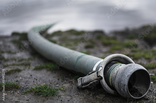 Close up dramatic moody shot of waste pipe that goes into a river on a cloudy day photo