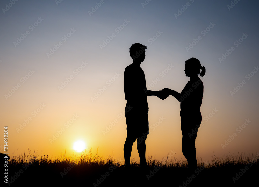 Silhouette of lovely couple holding by hands on beautiful sunset