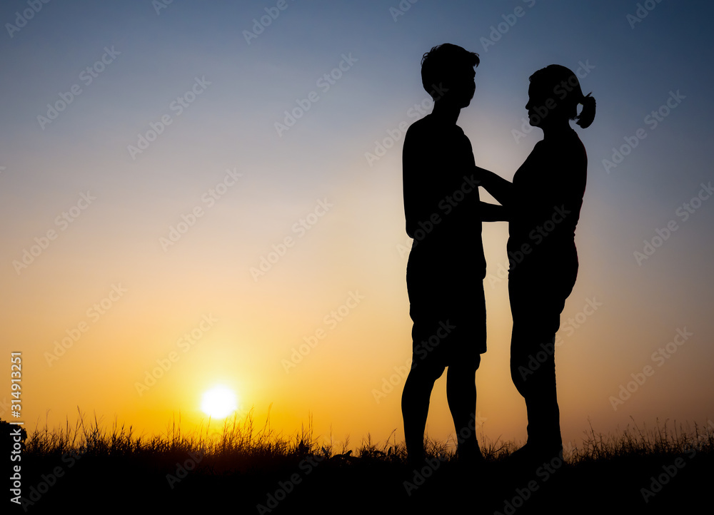 Silhouette of lovely couple holding by hands on beautiful sunset