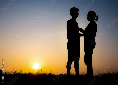 Silhouette of lovely couple holding by hands on beautiful sunset © showcake