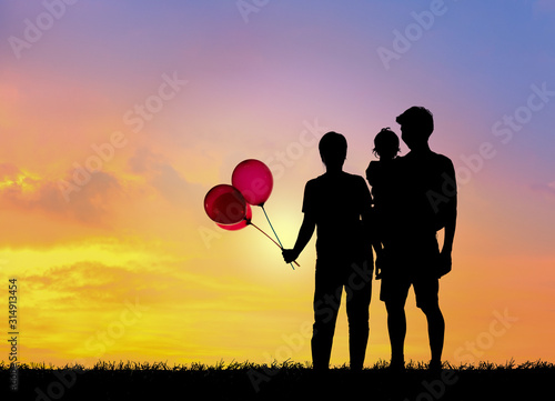 Silhouette family,father, mother and children holding balls against the sunset.