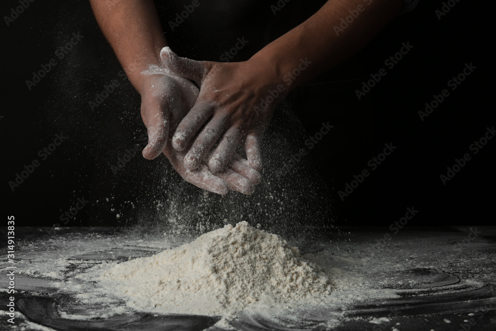 Baker with flour at dark table, closeup