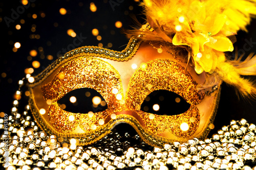Golden Carnival mask on black background with silver beads. Mardi Gras concept. Close-up