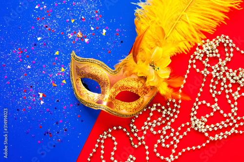 Fototapeta Naklejka Na Ścianę i Meble -  Golden Carnival mask on geometric colored background with sparkles and silver beads. Mardi Gras concept