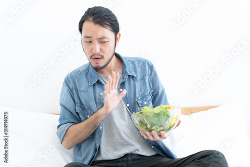 Young Asian man does not want to eat and has no appetite not eat salad Fototapeta