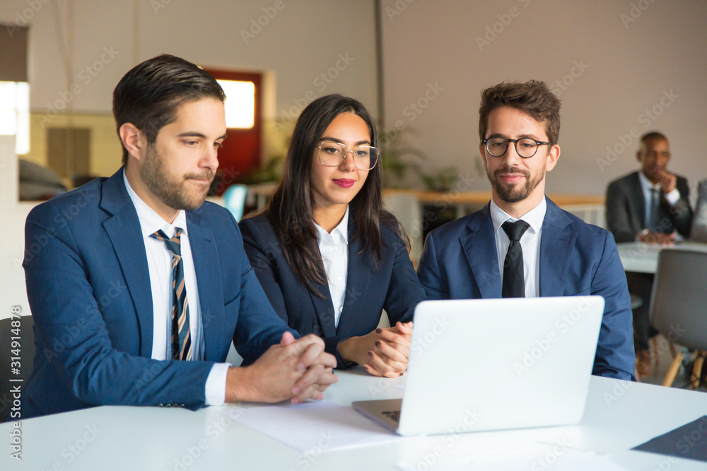 Confident business people looking at laptop. Cheerful businessmen and businesswoman reading information from laptop. Business concept Confident business people looking at laptop. Cheerful businessmen and businesswoman reading information from laptop. Business concept