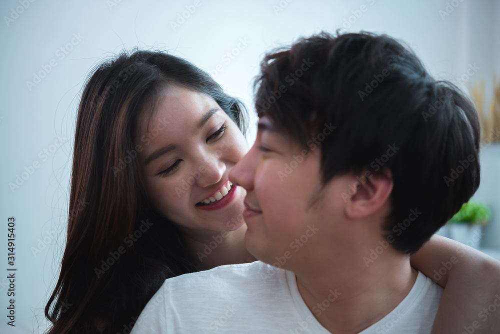 smiley young happy couple lying together in white bed