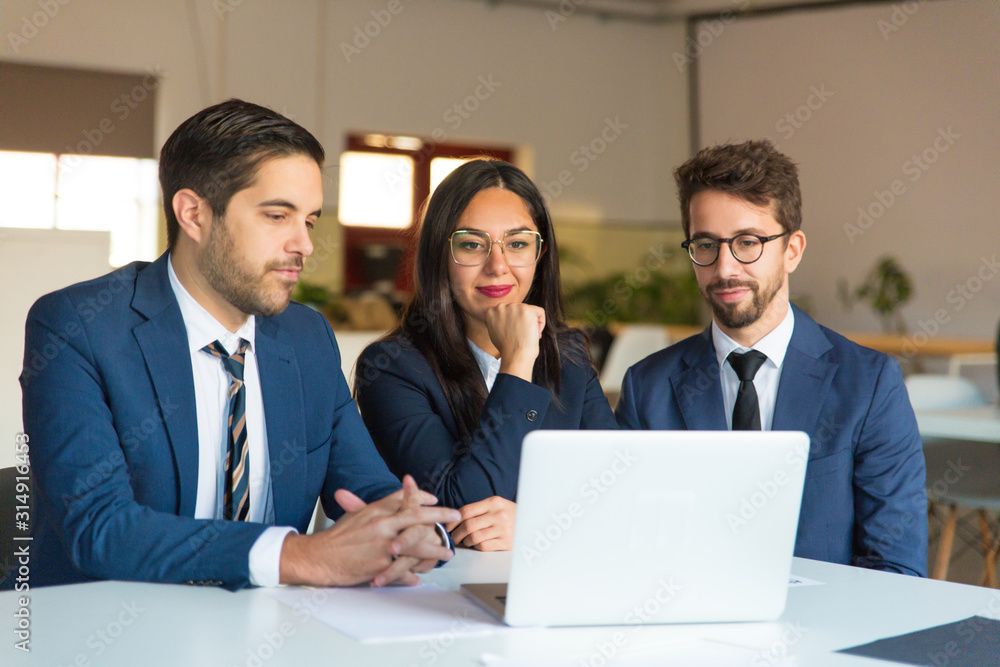 Confident office worker looking at laptop. Cheerful businessmen and businesswoman reading information from laptop. Business concept