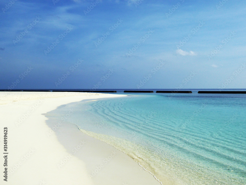 Menschenleerer Sandstrand mit Blick auf das Meer auf dem Rasdhoo Atoll (Malediven) bei Sonnenschein und blauem Himmel