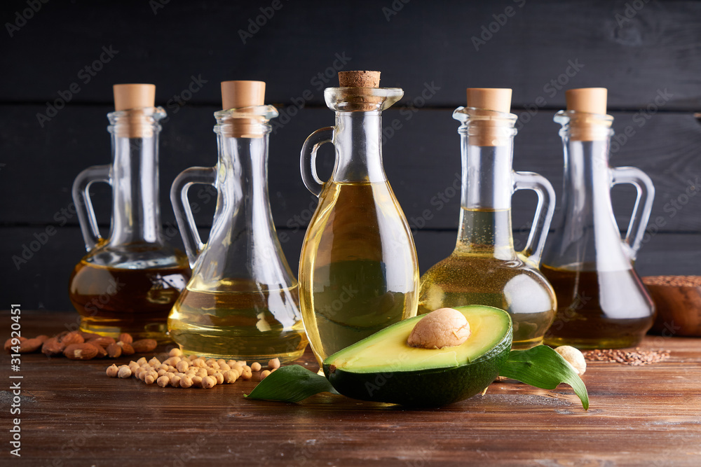 Useful vegetable oils in glass bottles. Avocado oil, chickpea oil, linseed oil, peanut oil, almond oil. Dark wooden background Useful vegetable oils in glass bottles. Avocado oil, chickpea oil, linseed oil, peanut oil, almond oil. Dark wooden background
