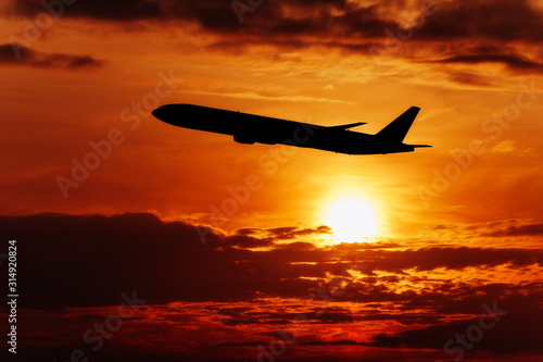 Airplane In The Sky At Sunset. Travel background with passenger plane.