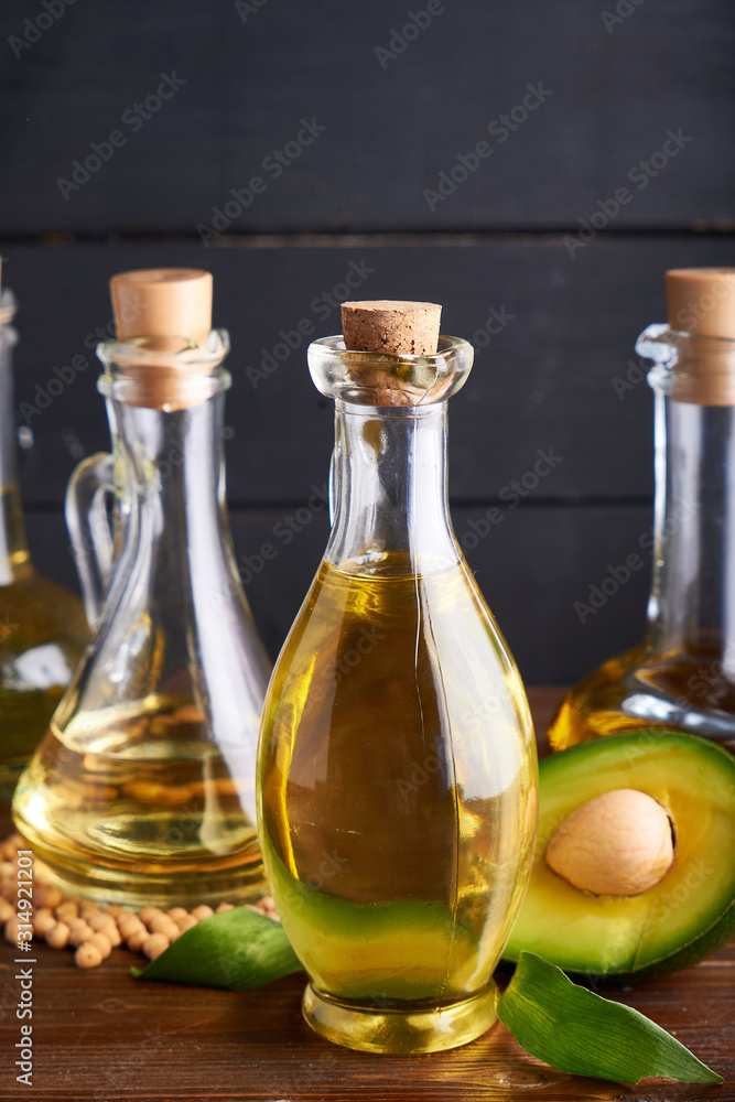 Useful vegetable oils in glass bottles. Avocado oil, chickpea oil, peanut oil, almond oil. Dark background Useful vegetable oils in glass bottles. Avocado oil, chickpea oil, peanut oil, almond oil. Dark background