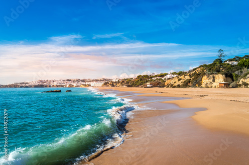 Waves craching against sandy beach in Albufeira resort village in Algarve  Portugal at sunset.