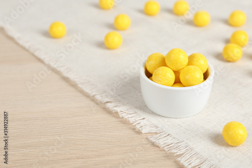 Tasty lemon drops on wooden table. Space for text