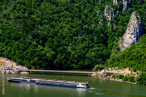 Cruise ship passing by rock sculpture of Decebalus in Danube gorge photo