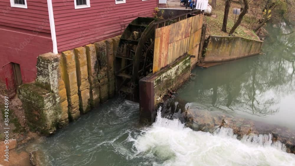 Wide shot of a traditional functional watermill by an old building