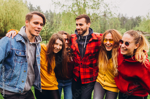 Funny selfie with friends. company of cheerful friends making selfie and smiling while standing outdoors. people wear red and yellow jumpers. young people resting in nature, talking and laughing