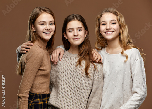 Cute happy girls embrassing, on brown background photo
