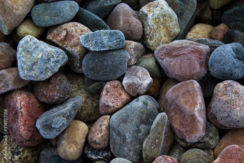 Multi-colored stones in the frost covered with hoarfrost