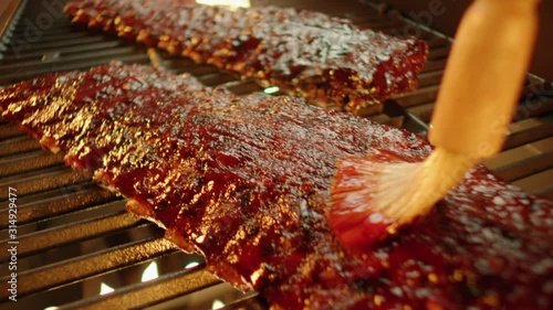 Rack of ribs turned and basted on flaming grill