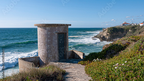 Round, concrete building at a beautiful viewpoint overlooking cliffs and the Atlantic ocean. Taken in Colares, Portugal.